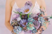 a pastel wedding bouquet with lilac, purple, blue and iridescent blooms, greenery and berries is a chic idea