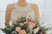 a pretty winter wedding bouquet of pink and blush blooms, berries and various kinds of greenery is a lovely idea for a winter bride