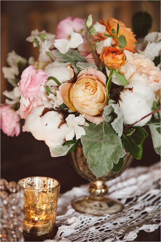 a refined wedding centerpiece of a gilded vase with pink, yellow and orange blooms, foliage and cotton is a beautiful solution
