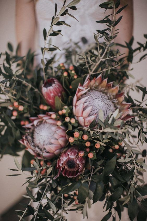 a relaxed and pretty wedding bouquet of king proteas, lots of greenery branches and berries is great for a summer wedding
