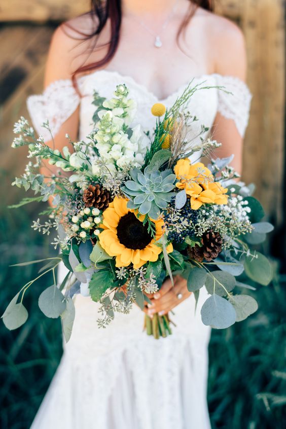 a rustic wedding bouquet of sunflowers, white blooms, berries, billy balls, pinecones, a succulent and lots of greenery is great for both fall and summer