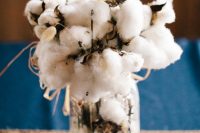 a rustic wedding centerpiece of a jar with cottona nd bunny tails is a super soft and cozy idea for a rustic fall or winter wedding