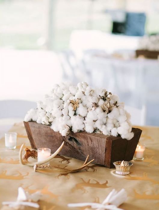 a rustic wedding centerpiece of a rich-stained wooden box filled with cotton, candles and antlers is a gorgeous idea to go for
