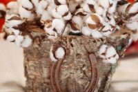 a rustic wedding centerpiece of a tree stump filled with cotton and a horseshoe is a lovely and cozy idea that you can DIY