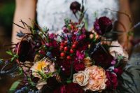 a sumptuous color wedding bouquet with fuchsia, deep red and hot pink blooms, lavender, greenery and some berries for a bold fall wedding