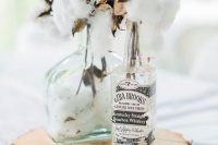 a super relaxed wedding centerpiece with cotton in bottles on a wood slice looks cute and soft and you can totally DIY it