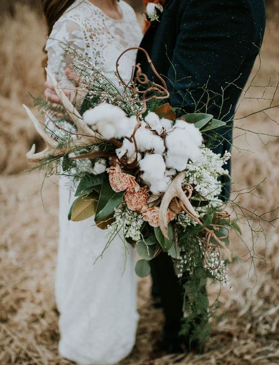 a textural woodland bouquet with antlers, cotton, gold and green leaves, pink and white blooms is a lovely idea for a boho or woodland bride