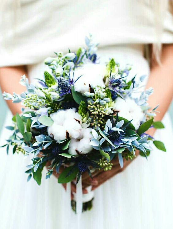 a wedding bouquet with cotton, greenery and blue thistles looks textural and very interesting is a lovely idea for a neutral winter wedding