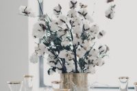 a wedding centerpiece of a brass vase and cotton branches looks wow and cute for winter and can be easily DIYed