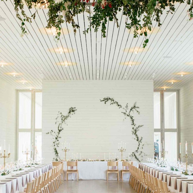 a white planked wall with greenery branches is an adorable idea for a rustic minimalist wedding and is easy to make yourself