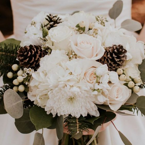 an all-neutral wedding bouquet of white roses, dahlias, berries, pinecones, evergreens and eucalyptus is a lovely idea for winter