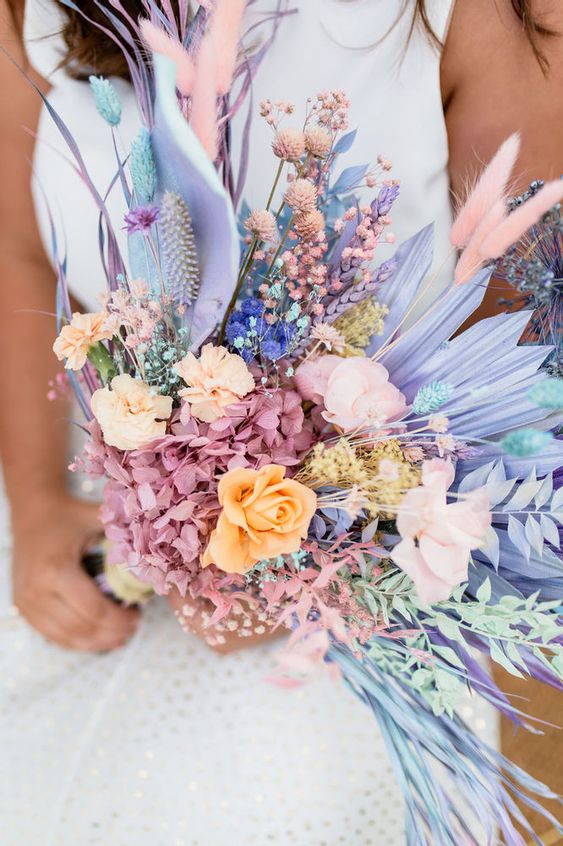 an iridescent edding bouquet composed of lilac fronds, pink and orange blooms, pink hydrangeas and bunny tails plus foliage