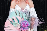 an iridescent wedding bouquet of blue and blush spray painted tropical fronds, iridescent blooms and leaves and colorful ribbons