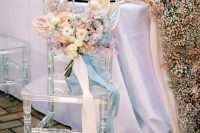 an iridescent wedding bouquet with blush, blue, white and iridescent blooms and long ribbons is wow