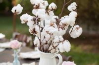 cotton branches in a jug, pink roses and vintage books for decorating the wedding tablescape and giving it a cozy feel
