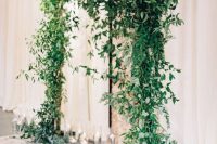 a beautiful and super lush greenery wedding arch and floating candles in glasses around is a very cool and fresh idea for a modern wedding