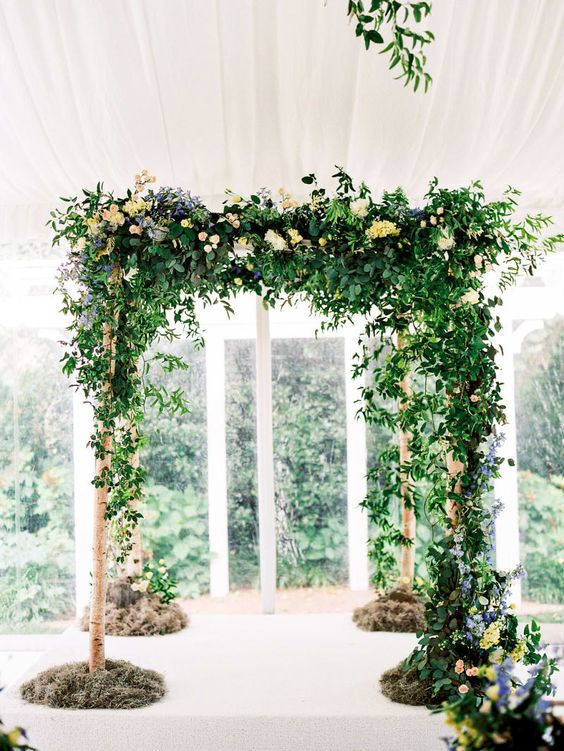 a beautiful greenery wedding arbor decorated with just a bit of pastel blooms is a stylish idea for a spring or summer wedding