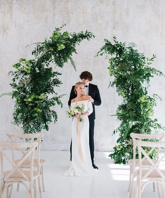 a beautiful lush indoor wedding altar of two parts, with greenery and some green hydrangeas is great for a chic modern wedding