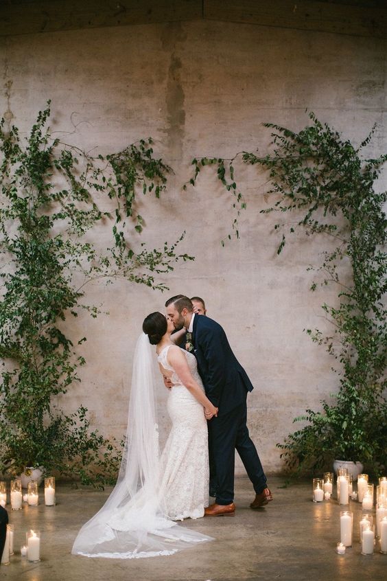 a greenery wedding altar surrounded with candles is a cool idea for a modern wedding, both indoors and outdoors