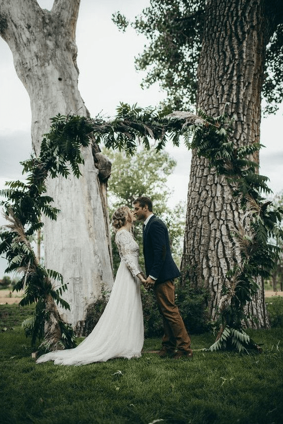 a hexagon wedding arch fully covered with greenery and ferns will be a perfect match for a woodland wedding