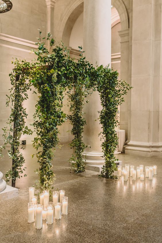 a lovely greenery wedding chuppah surrounded with candles is a cool idea for a chic wedding in spring or summer