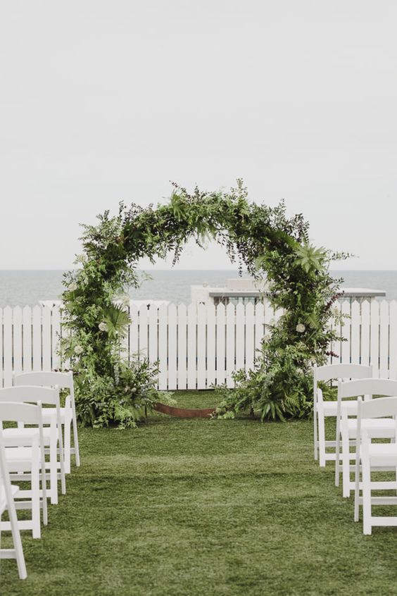 a lush greenery round wedding arch with much texture is a cool idea for any spring or summer wedding