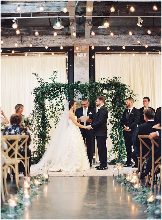a lush greenery wedding arch like this one will easily create an outdoor feeling indoors