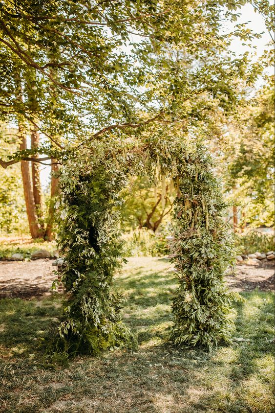 a lush greenery wedding arch with branches and twigs is a cool idea for a fall or woodland wedding