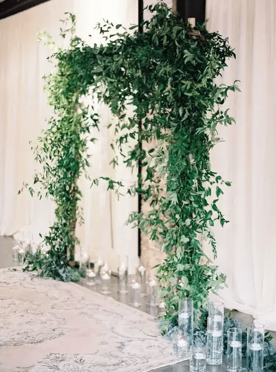 a lush greenery wedding arch with floating candles around is a cool modern wedding solution