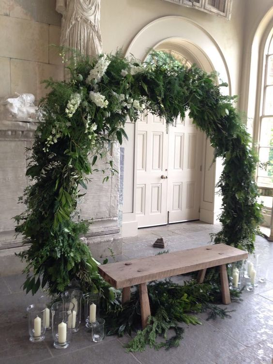 a lush round greenery wedding arch with a bit of white blooms is a cool idea for many weddings