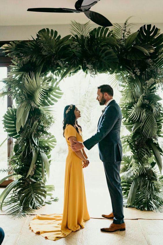 a lush tropical wedding arch covered with fronds is a pretty idea for a modern tropical wedding