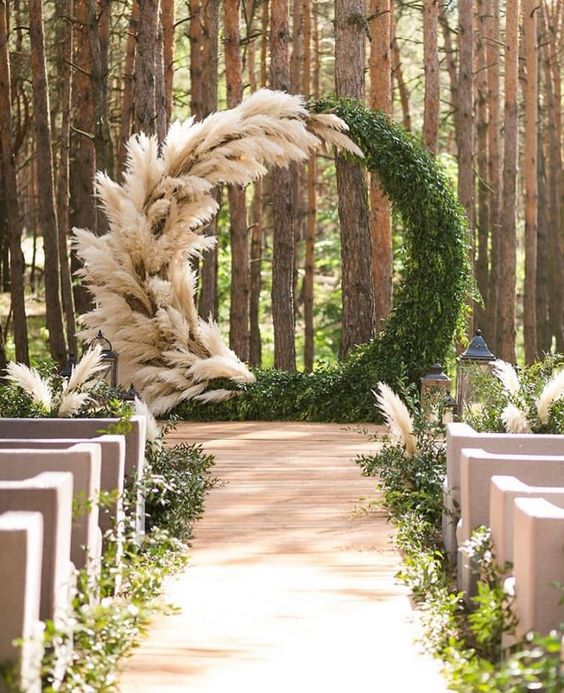 a massive round wedding arch covered with lush greenery and pampas grass is a gorgeous idea for a modern and trendy wedding