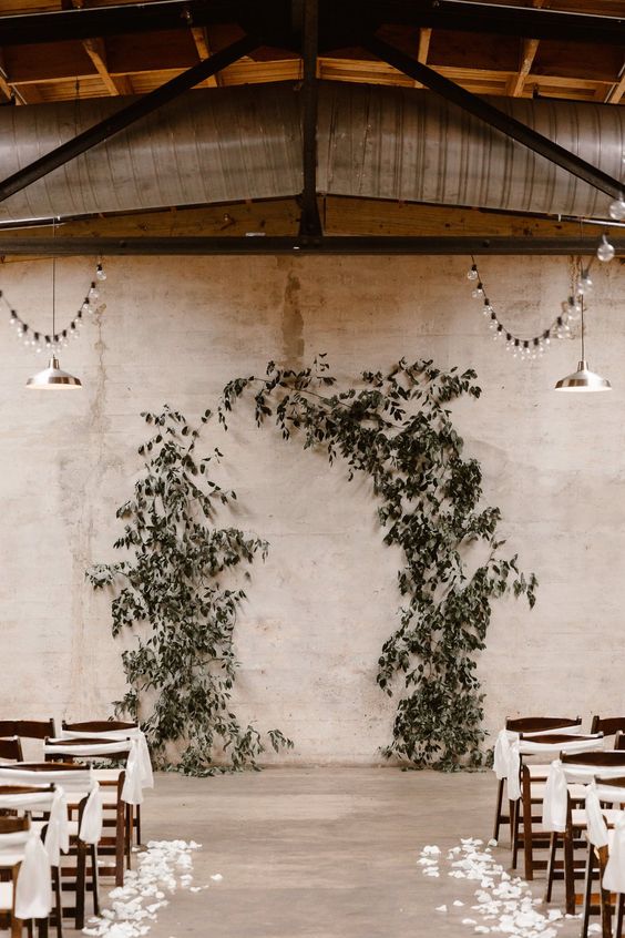 a pretty indoor greenery altar and white petals on the floor are a cool combo for a modern wedding
