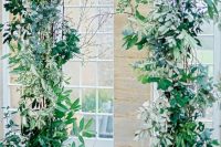a pretty wedding arch decorated with lush and wild greenery and branches all over is a stylish idea for a nature-inspired wedding