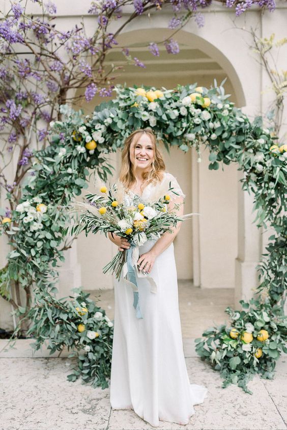 a round greenery wedding arch with lemons is a cool solution for a southern wedding or a tropical one