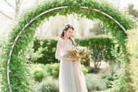 a round metal wedding arch covered with lush greenery is a lovely solution for a garden wedding, it can be used in spring or summer