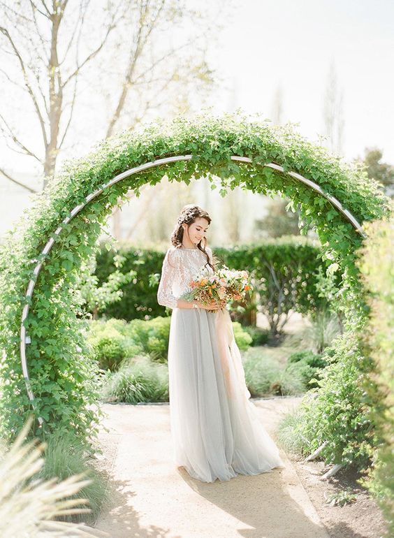 a round metal wedding arch covered with lush greenery is a lovely solution for a garden wedding, it can be used in spring or summer