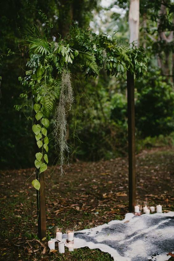 a simple woodland wedding arch covered with some greenery is a cool idea for a woodland wedding