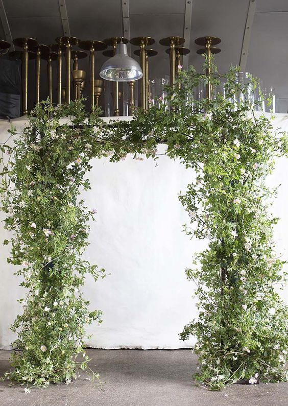 a super lush greenery wedding arch with a bit of white blooms is very textural and fresh, great for a spring wedding