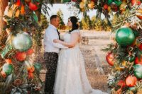 02 a Christmas wedding arch decorated with evergreens, pinecones, bold green, red, yellow ornaments and with glitter is an ultimate idea
