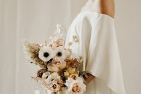 02 a lovely modern winter bridal outfit with an off the shoulder plain wedding dress plus a pastel wedding bouquet with grasses
