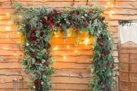 03 a gorgeous Christmas wedding arch shaped as a frame, covered with evergreens, greenery, red roses and with lots of candle lanterns around