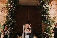 07 a jaw-dropping Christmas wedding arch covering the doorway, with los of greenery, blush and red blooms and floating candles is amazing