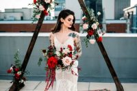 08 a bold Christmas wedding arch of stained wood, blush and red roses and greenery plus a bold boho rug is a stylish idea