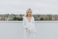 14 a pretty and simple modern winter bridal look with a plain wedding dress with a depe V-neckline, long sleeves and a train plus a lush white wedding bouquet
