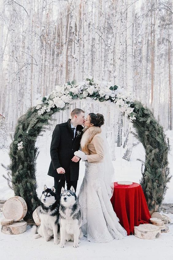 a round wedding arch of evergreens and with lots of white blooms on top is a fantastic idea for a snowy Christmas wedding