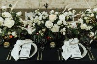 16 a bold modern winter wedding tablescape with a black tablecloth and plates, with neutral napkins and menus plus neutral blooms