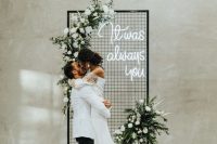 21 a modern winter wedding backdrop with white blooms and greenery, a neon sign and pillar candles around