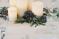 22 a modern winter wedding centerpiece of pillar candles, greenery and privet berries is a stylish and chic idea