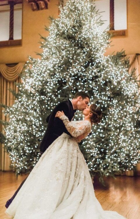 a large Christmas tree fully covered with lights is a perfect Christmas wedding backdrop, what can be more natural than this